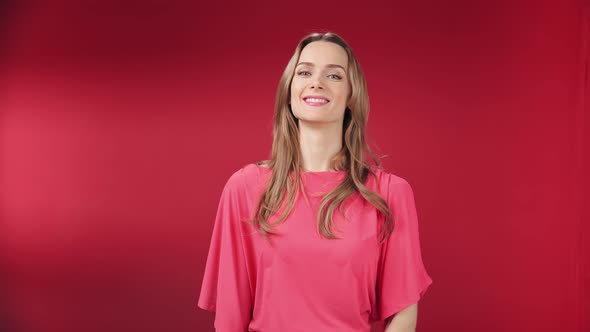 Portrait of Smiling Pretty Blonde Girl Showing Gesture Ok Isolated at Red Studio Background