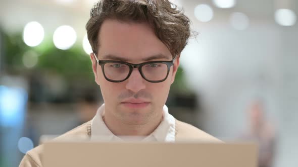 Close Up of Young Male Designer with Laptop Looking at the Camera