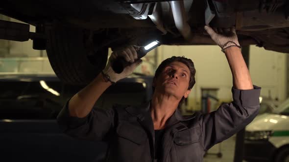 Adult caucasian car mechanic looking with light