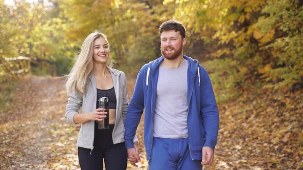 Happy Young Couple Strolling Through the Woods Contemplating the Beauty of Autumn Nature After a Run