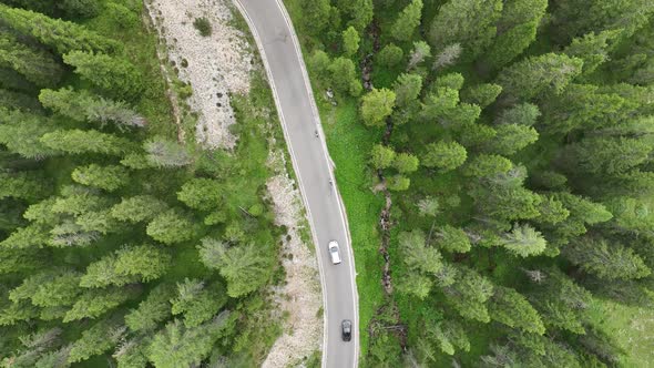 Flying above motorbikers and cyclists riding down a winding mountain road in the Dolomites