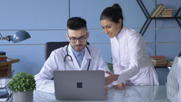 A Doctor and a Nurse work at a Computer in the Hospital Office. Professional team of scientists