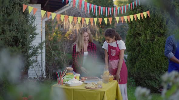 Wide Shot of Caucasian Woman and Mixedrace Teenage Girl Setting Table As African American Man