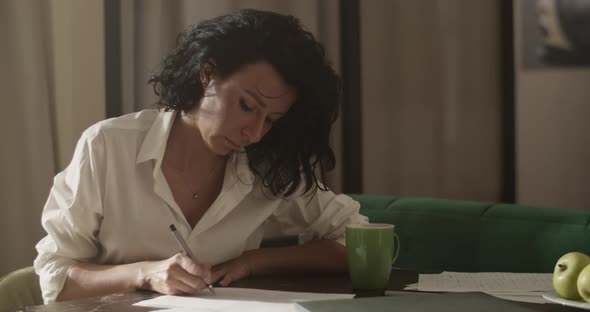 Businesswoman Drinking Coffee and Making Notes