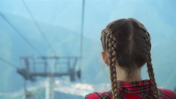 Adorable Happy Little Girl in the Cabin on the Cable Car in Mountains in the Background