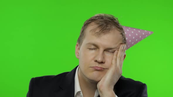 Drunk Sleepy Young Businessman with Hangover in Festive Cap Falling Asleep