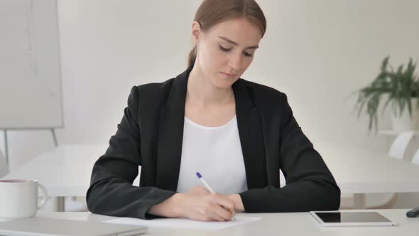 Young Businesswoman Writing on Paper