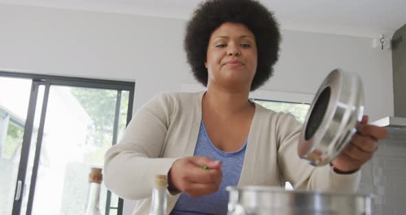 Video of happy plus size african american woman preparing meal