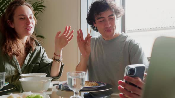 Couple eating at home and having video call on smartphone