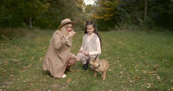 Joyful Mother and Daughter Playing with Dog in a Par