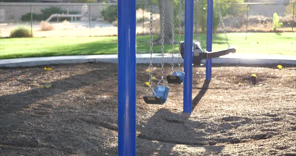 Slide right through a sunny kids park playground with an empty swing set.