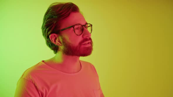 Young Bearded European Man with Glasses Having a Phone Call Via Airpods Medium Closeup Yellow