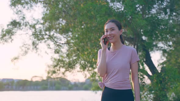 Asian young woman stand outdoor use mobile phone call talk with friend.