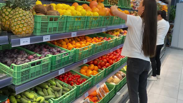 Young Woman Standing By Fruit and Vegetables Stand Market Choosing Grapefruit