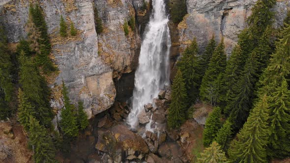 Flying over a green forest around a big waterfall in the mountains. Waterfall Aerial View.