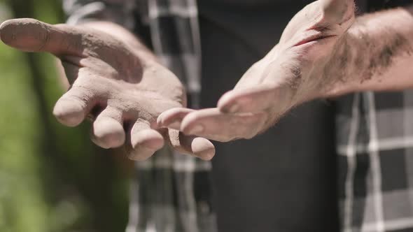 The worn-out hands of the gardener, the farmer's dirty hands. Dry soil in the hands, drought.