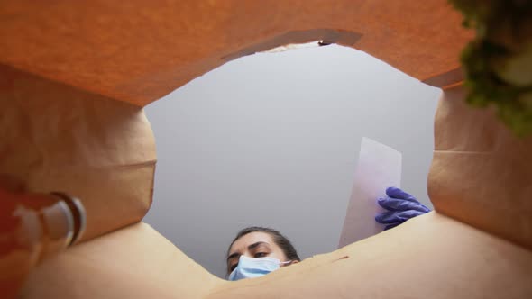 Woman in Gloves and Mask with Food in Paper Bag