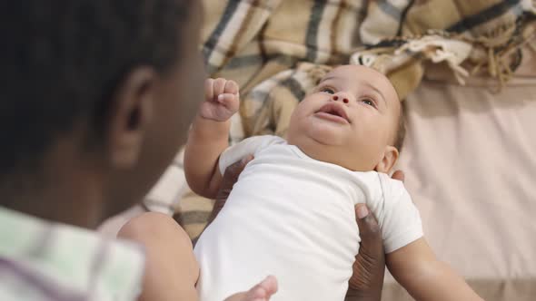 African Father Holding and Playing with Adorable Baby Son at Home