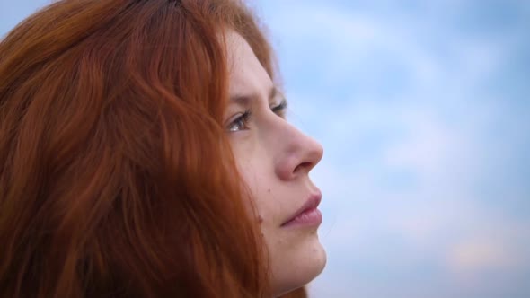 Beautiful Redhead Woman Looking up Mentally Praying with Wind Blowing Hair