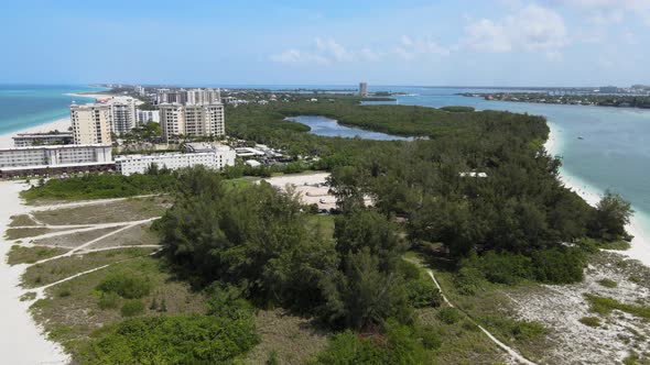 Flying over the point of a large white sand beach. The Florida beach is next to state park with seve