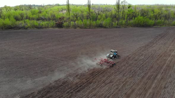 A Tractor Cultivates the Soil in the Field