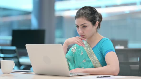 Young Indian Woman Thinking while using Laptop