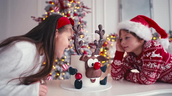 Two Caucasian Kids Boy and Girl are Sitting Near the Christmas Cake