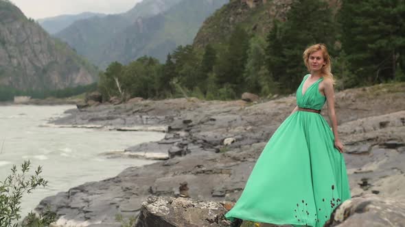 Young Woman in a Long Flowing Dress on the Background of the River and Mountains. Coloring a Woman