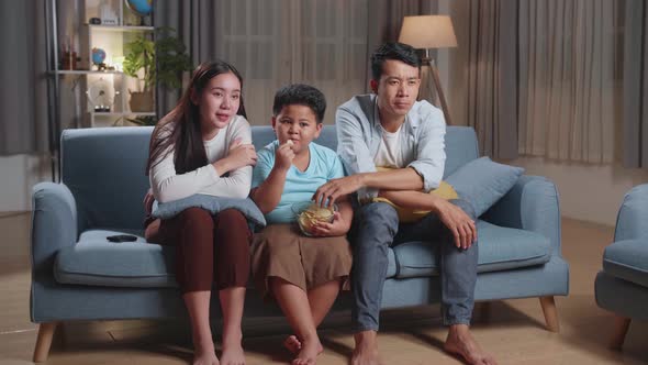 Leisure And People Concept, Asian Family Eating Potato Chips And Watching Tv At Home
