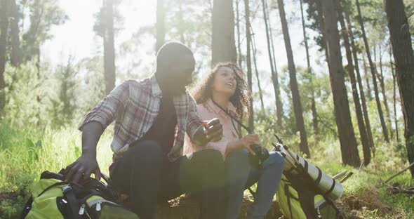 Smiling diverse couple sitting and embracing in countryside