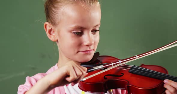 Schoolgirl playing violin in classroom at school