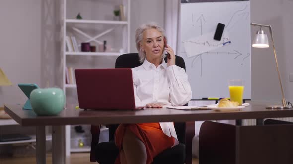 Confident Middle Aged Businesswoman with Serious Facial Expression Talking on Phone Sitting in