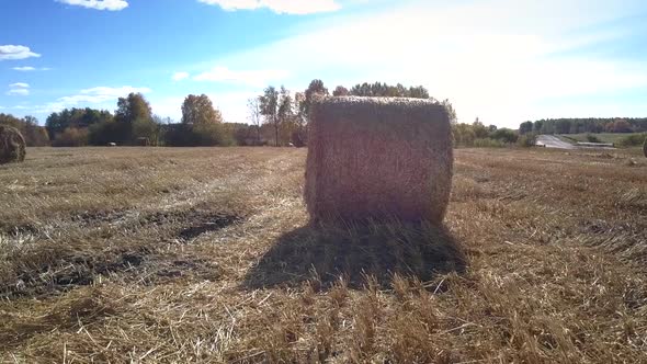 Close Motion Around Large Straw Roll on Vast Field