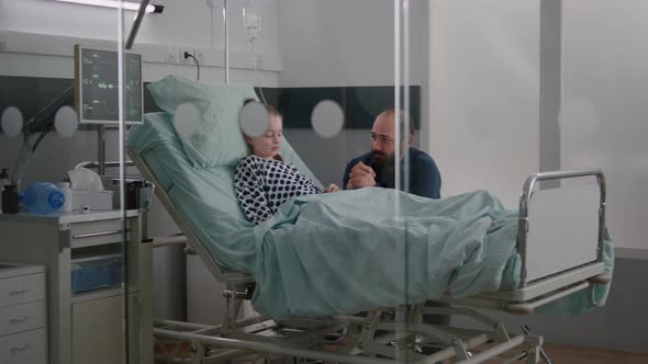 In Hospital Ward Sick Girl Patient Sleeping While Worried Father Praying for Sickness Recovery