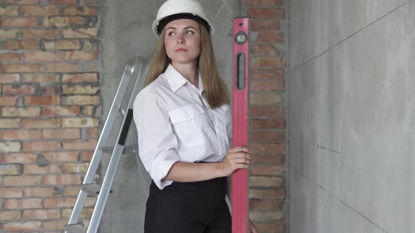 Girl engineer builder at a construction site holds a level in hands.