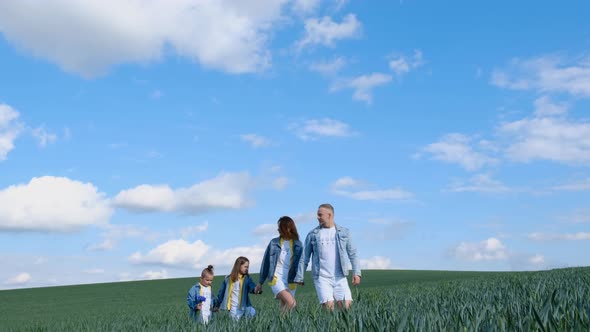Family in the Field on a Background of Blue Sky