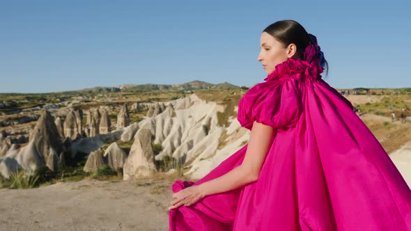 Young Tall Girl Model Runs in a Long Purple Dress with a Tail in the Mountains