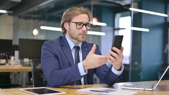 Businessman Upset By Loss on Smartphone 