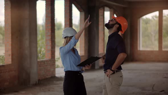 Two Engineer In Helmet Inspecting Building. Developer On Construction Site. Home Plan Scheme.