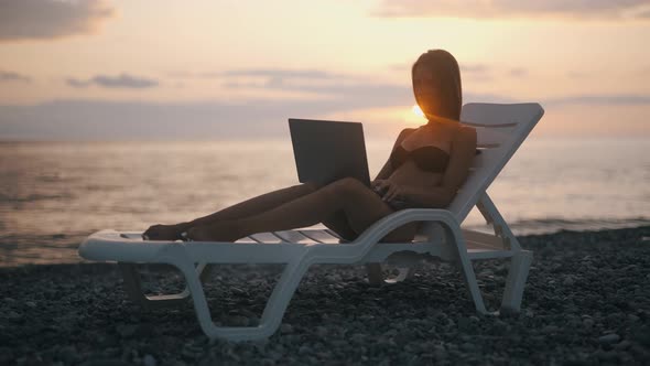 A Female Freelancer is Working on Laptop Near Sea