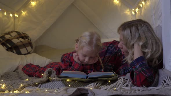 Mom Reads a Book to Her Daughter