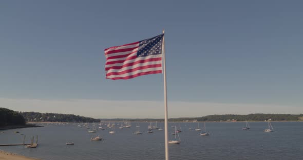 Aerial Pan Around of an American Flag and Boats Anchored at Harbor in Glen Cove