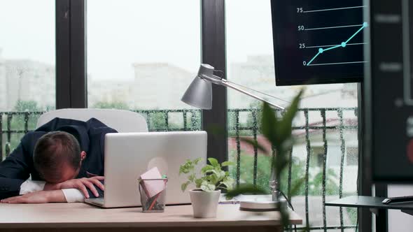 Overworked Businessman Sleeps with His Head on the Office Desk