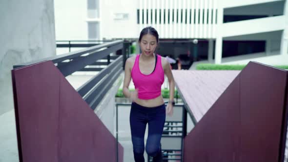 Young Asian woman running and jogging on street in urban city park