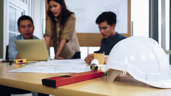 Team of young Asian architects and engineer discussing on construction site.