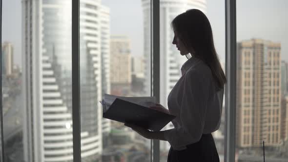 Silhouette of a Young Business Woman Against the Background of a Large Window