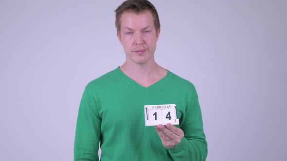 Young Stressed Man Giving Thumbs Down with Calendar Block