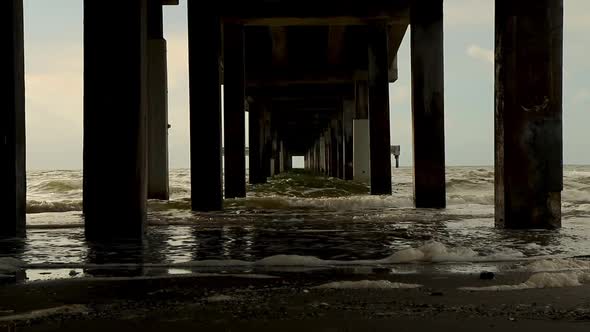 Waves on the beach under a pier