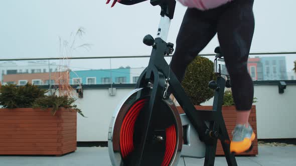 Athletic Woman Riding on Spinning Stationary Bike Training Routine on House Rooftop Weight Loss