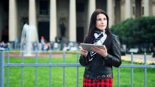 Pretty Woman with a Tablet in Her Hands Looking for a Road in a Tourist City